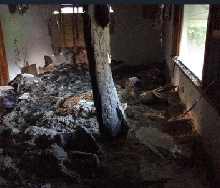 Drywall and insulation cover the ground in a living room after collapsing from the ceiling