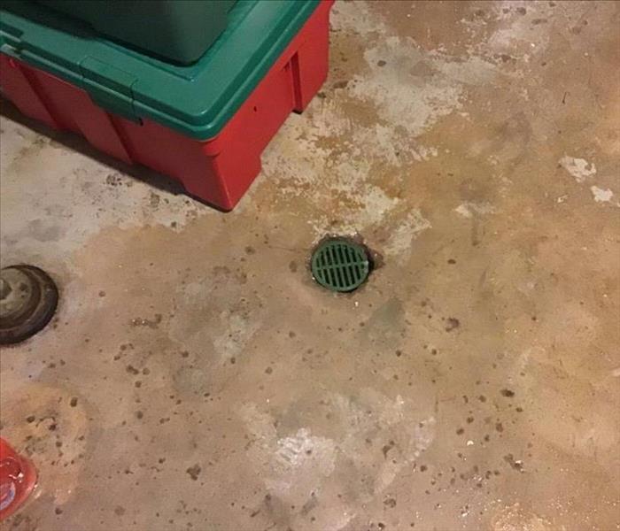 A photo of a floor drain in a basement.