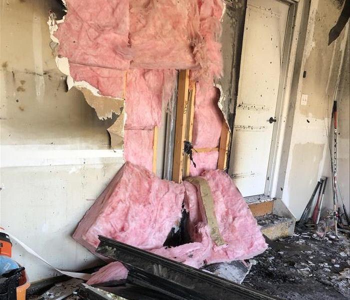 A photo of a fire that happened in a garage with damage to the dry wall and insulation